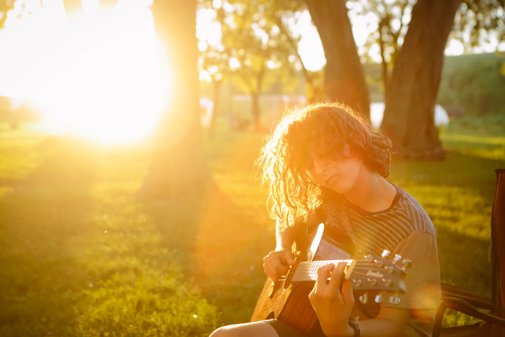 A youth playing guitar at Proclaim during golden hour